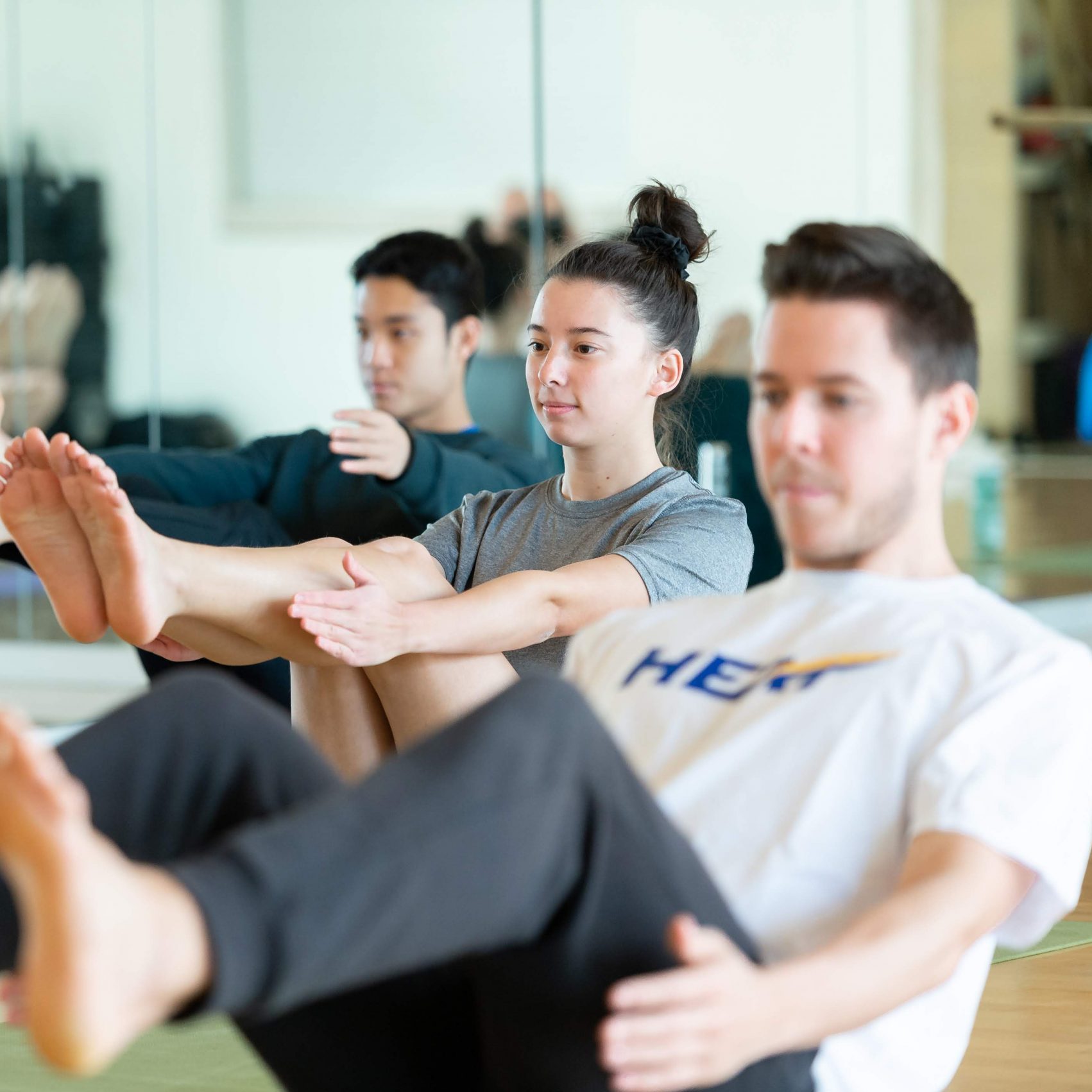 Students in a yoga class performing a seated core exercise.