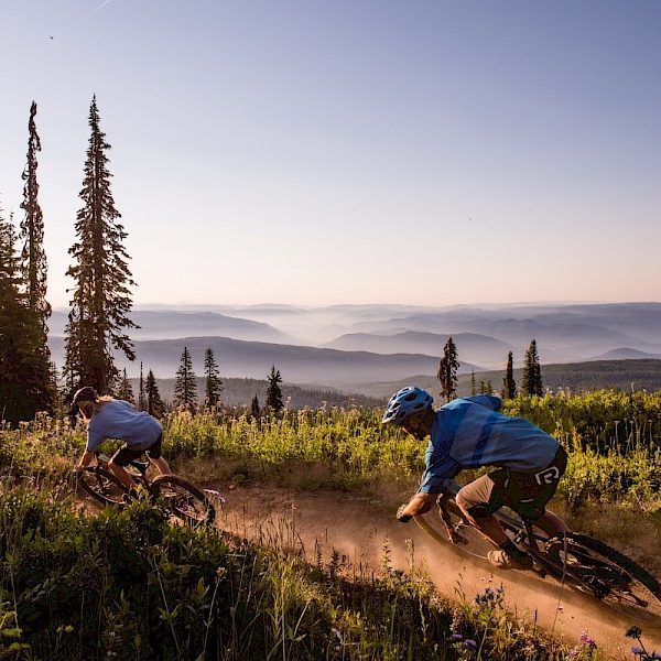 Mountain bikers on a trail with view of the mountains.
