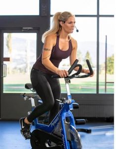A fitness instructor leading a spin class on a stationary bike.