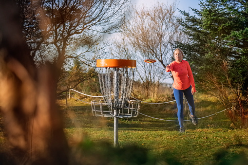Person playing a game of disc golf outdoors in a park.
